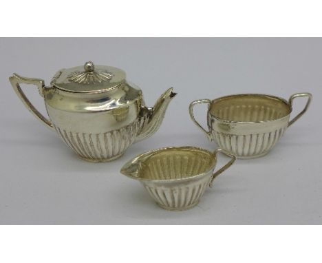 A dolls house miniature three piece silver tea service