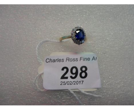 A sapphire and diamond cluster ring, the oval cut sapphire in raised claw mount above a border of brilliant cut diamonds.   C