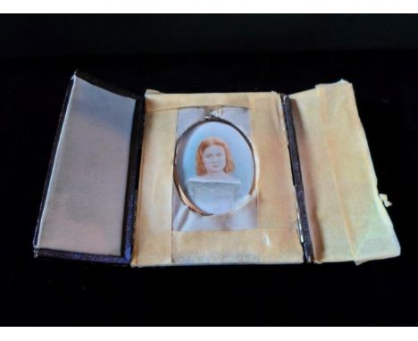 A portrait miniature of a young girl, watercolour, mounted in an oval brass frame and fitted to a red leather case.