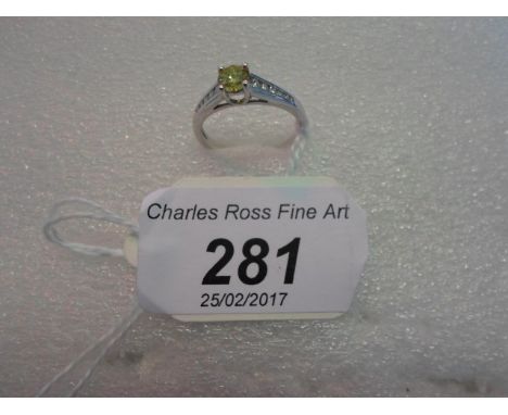 A single stone fancy coloured canary yellow diamond, circular cut and claw mounted above tapered diamond set shoulders, to pl