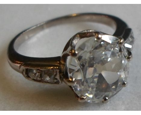 A single stone diamond ring, the old oval shallow cut stone in simple claw mount, above tapered two stone diamond shoulders, 