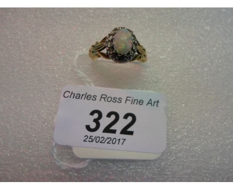 An opal and diamond cluster ring, the oval opal within a border of single cut diamonds to carved 18 carat gold shoulders.