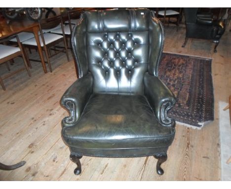 A green leather upholstered button wing back armchair on front cabriole supports, (81cm wide).
