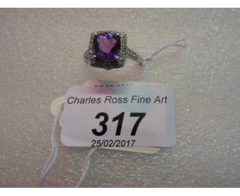 An amethyst and diamond cluster ring, the cushion shaped amethyst within a border of brilliant cut diamonds, diamond set shou