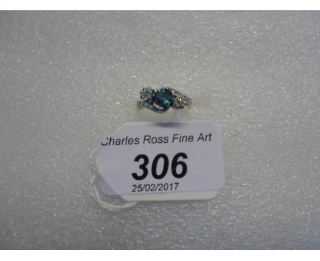 A three stone blue topaz and diamond crossover ring, the circular cut stones in claw mounts to a textured two coloured mount 