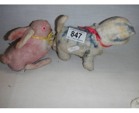 A vintage key wind clockwork cat and a vintage rabbit toy.