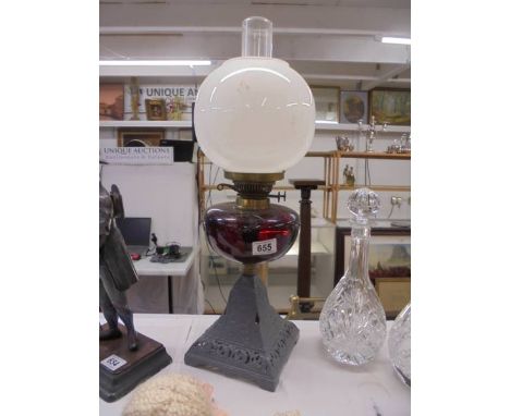 A Victorian oil lamp on cast iron base and with ruby glass font. COLLECT ONLY.