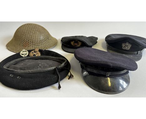 A BRITISH WW2 STEEL HELMET AND AN ASSORTMENT OF PEAKED CAPS the first complete with its scrim-net, the left side painted with