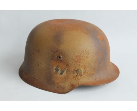 A WWII GERMAN HELMET with a worn SS type decal to side, impressed number to inside '538' rusted surfaces