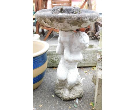 A painted figural concrete bird bath, the circular bath raised on a figure of a putto, 61cm high, 35cm wide, together with a 