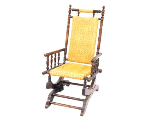 An American rocking chair, with bobbin turned supports, on a yellow boxed design upholstered seat and back, 108cm high, 55cm 