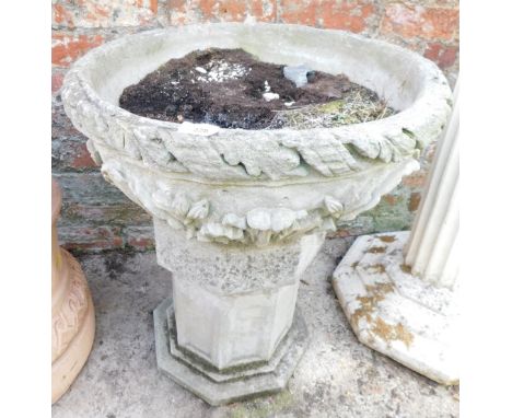 A reconstituted stone planter, the bowl with leaf moulded and applied fleur de lis decoration on an associated octagonal base