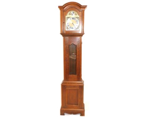 A 20thC oak cased longcase clock, with arched hood and brass dial with silvered chapter ring and spandrels, pendulum and weig