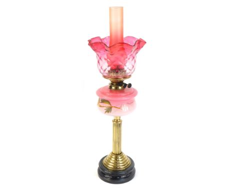 A Victorian cranberry glass oil lamp, with a cranberry glass flared shade and chimney, and a painted floral reservoir on bras