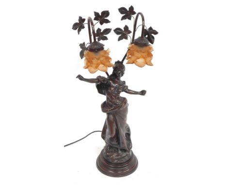 An Art Nouveau bronze effect table lamp, of a semi clad female, with fluted orange shades and vine supports, 79cm high.