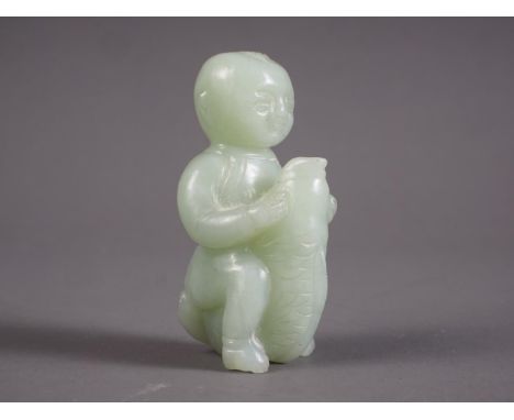 A Chinese carved celadon jade figure of a child astride a carp, 2" high