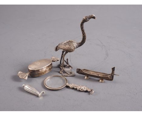 A white metal flamingo, a similar bonbon pill box, a magnifying glass and a white metal Maori canoe