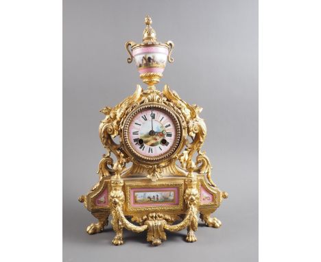 A 19th century gilt brass mantel clock with inset porcelain panels and vase finial, on lion paw feet, 15" high