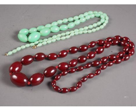 A string of cherry amber Bakelite graduated oval beads, largest 29mm wide, 61g, and a jade coloured graduated bead necklace, 