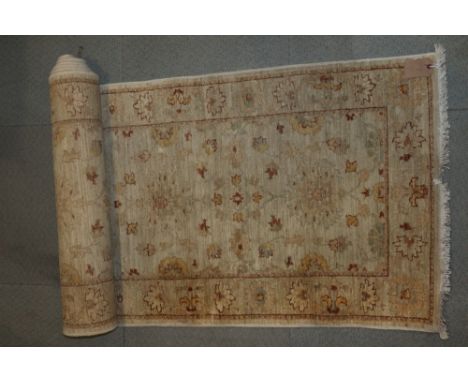 A Persian runner with tendril and scroll in shades of brown on a cream ground, 118" x 30" approx