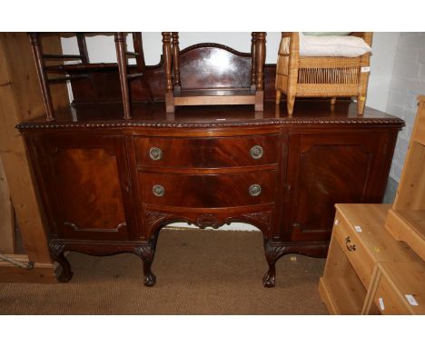 A 1930s carved mahogany break bowfront sideboard of Chippendale design with raised ledge back over two cupboards and central 