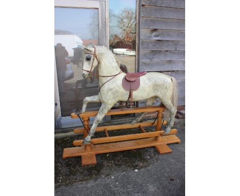 A carved and painted wood dappled grey rocking horse, by Harold Wakefield, Boston, with horse hair mane and tail, base 66" lo