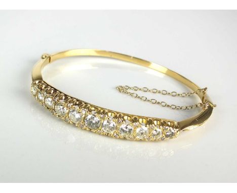 A Victorian style diamond set hinged bangle, designed as a row of eleven graduated brilliant cut diamonds interspersed with t