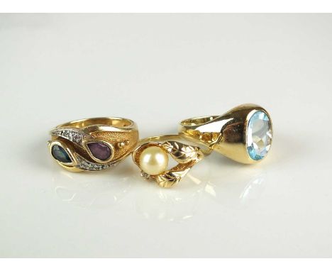A blue topaz ring, stamped ‘14kt’, size P, together with a sapphire and ruby stylised crossover ring, stamped ‘14k’, size M 1