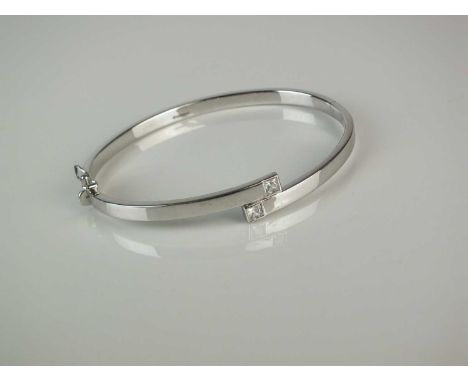 A 9ct white gold hinged bangle, set with two square faceted cubic ziconia, hallmarked Sheffield 2004, weight approx 7g