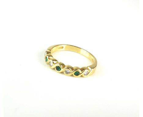 An 18ct gold seven stone emerald and diamond ring, the round faceted stones collet set within stylised yellow gold scrolling 