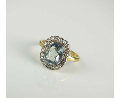 An 18ct gold aquamarine and diamond cluster ring, the cushion cut aquamarine collet set in white gold within a border of face