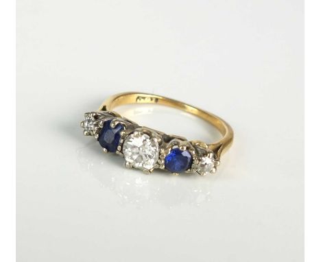 An early 20th century five stone ring, designed as three graduated old cut diamonds interspersed with two untested blue stone