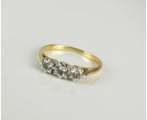 A graduated three stone diamond ring, the brilliant cut diamonds claw set in white metal to yellow metal shank, stamped '18ct