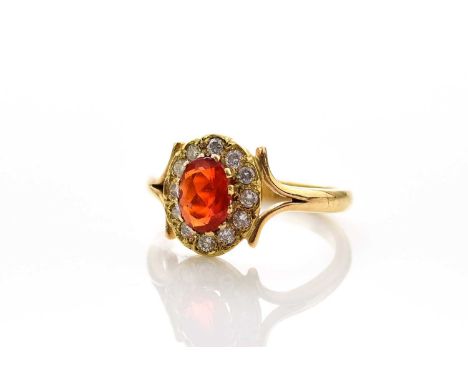 An 18ct gold fire opal and diamond ring, designed as a central oval mixed cut fire opal claw set within a border of twelve br