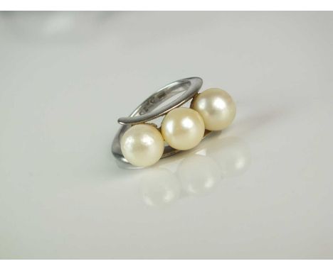 A three stone cultured pearl ring, the three uniform cultured pearls mounted to stylised crossover white metal shank, stamped