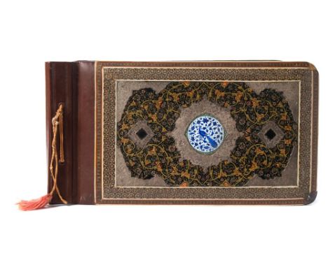 A Persian photograph album: the front board with central circular enamel panel of an exotic bird, enclosed by a silver frame 