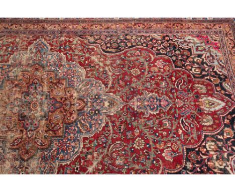 An Indo Persian carpet:, the wine cartouche field with a central pole medallion and all over floral, foliate, palmette and la