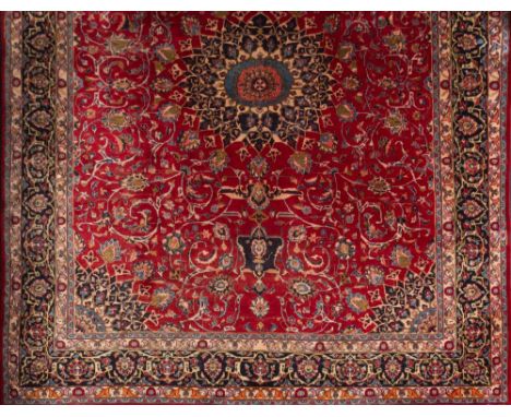 An Indo Persian carpet:, the madder field with a central indigo arabesque flowerhead and palmette pole medallion and all over