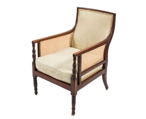 A Regency mahogany bergere armchair:, with curved upholstered panel back, cane panel sides with turned uprights to the termin