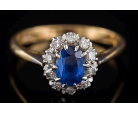 A sapphire and diamond oval cluster ring: the central, oval sapphire approximately 6.4mm long x 4.4mm wide x 2.3mm wide, with