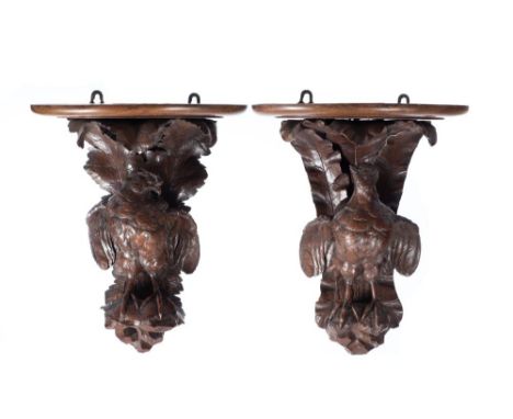 A pair of carved oak brackets: in the form of birds with partially outstretched wings, perched on foliate decorated backplate