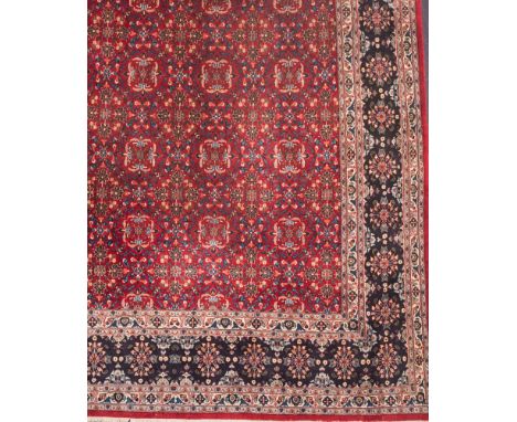 An Indo Persian carpet:, the wine field with an all over geometric design of flowerhead palmette medallions, in pastel blue l