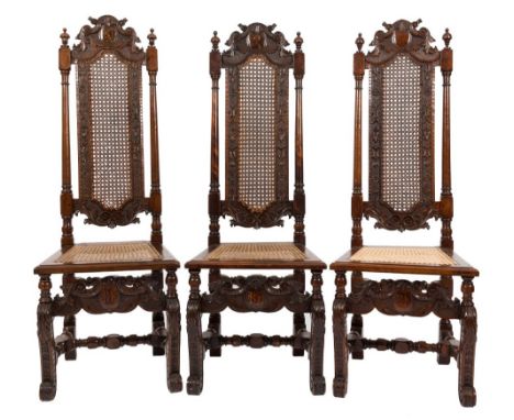 A set of four 17th Century carved walnut dining chairs:, the high cane panel backs with shaped foliate scroll and husk cresti