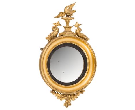 A Regency carved giltwood circular convex mirror:, surmounted by a figure of an eagle with wings outspread, perched on a tape
