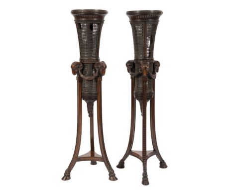 A pair of carved walnut and cane panelled torcheres:, of circular tapering form in the Regency taste, the tops with a reeded 