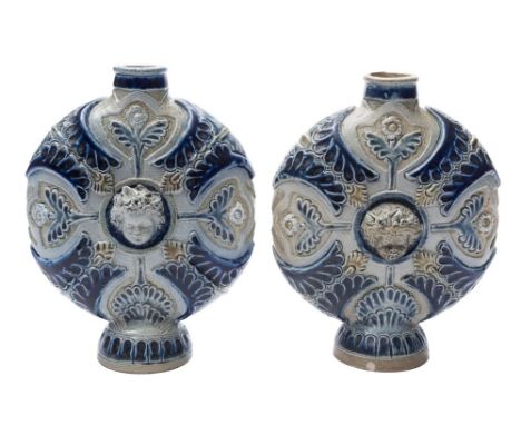 A pair of Martin Brothers salt glazed stoneware flasks or vases: of footed and flattened circular form with carved and applie