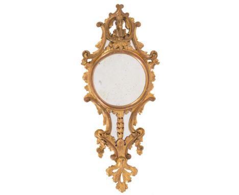 A carved giltwood mirror:, of cartouche-shaped outline with palmette, foliate scroll and pendant husk cresting, having a circ
