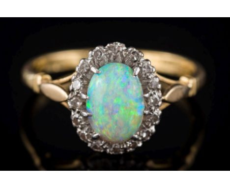 An opal and diamond oval cluster ring: the oval opal approximately 8.5mm long x 6.0mm wide x 2.7mm deep, within a surround of