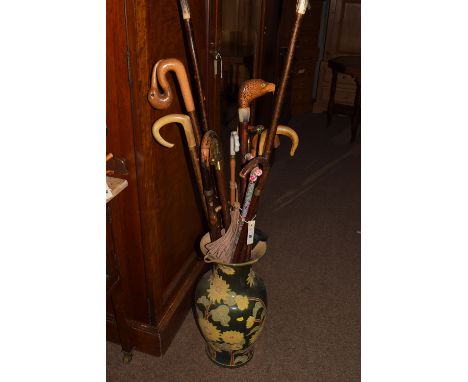 A collection of hand-made birds head rustic and other walking sticks, in a ceramic umbrella receiver.