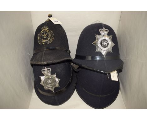 Two modern policeman's helmets, one with the front badge inscribed 'Bedfordshire Police'; a third with a badge 'Tynemouth Bor